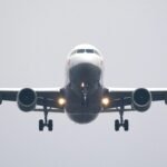 A commercial airliner captured head-on, preparing to land against a cloudy sky.